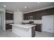 Modern kitchen with stainless steel appliances, a large island with a sink, and sleek, dark-stained cabinets at 2823 N 212Th Dr, Buckeye, AZ 85396