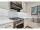 Modern kitchen featuring stainless steel stove with decorative hood and bright white subway tile at 2851 W Gold Dust Ave, San Tan Valley, AZ 85144