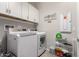 Bright laundry room with white washer, dryer, cabinets, and decorative 'Home Sweet Home' sign at 28931 N 64Th Dr, Phoenix, AZ 85083