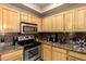 Updated kitchen features wooden cabinets, stainless steel oven and microwave, and granite countertops at 2929 W Yorkshire Dr # 1066, Phoenix, AZ 85027