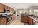 Modern kitchen featuring stainless steel appliances, wooden cabinets, granite countertops, and plenty of natural light at 3387 E Bluejay Dr, Chandler, AZ 85286