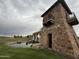Stone clubhouse exterior featuring a pond, complemented by a charming turret and lush landscaping at 36197 W Cartegna Ln, Maricopa, AZ 85138