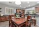 Inviting dining area showcases wooden table, surrounded by kitchen and living areas with natural light streaming through windows at 36197 W Cartegna Ln, Maricopa, AZ 85138
