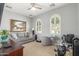 Comfortable living room with a grey couch, two windows, and a stationary bicycle at 36197 W Cartegna Ln, Maricopa, AZ 85138