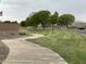 Long sidewalk winding through green grassy common area and mature trees creating a beautiful walking path at 36197 W Cartegna Ln, Maricopa, AZ 85138