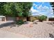 Charming home with a well-maintained, low-maintenance desert rock yard and mature shade tree in front at 4115 W Danbury Dr, Glendale, AZ 85308