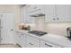 Modern kitchen with white cabinets, stainless gas cooktop, and stylish backsplash at 517 S 165Th Dr, Goodyear, AZ 85338