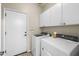 Functional laundry room with modern appliances, white cabinets, and direct access to the outside at 517 S 165Th Dr, Goodyear, AZ 85338