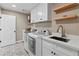 Well-equipped laundry room with modern machines, stylish flooring, sink and storage shelves at 6220 E Paradise Ln, Scottsdale, AZ 85254
