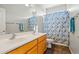 Bathroom with double sinks, wood cabinet, tile floor, and patterned shower curtain at 6245 W Maya Dr, Phoenix, AZ 85083