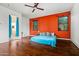 Bedroom with wood floors, bright orange accent wall, ceiling fan, and view to en suite bath at 6245 W Maya Dr, Phoenix, AZ 85083