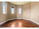 Bedroom features wood flooring, tan walls, and three windows with black blinds at 6245 W Maya Dr, Phoenix, AZ 85083
