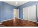 Bedroom boasts wood floors, blue walls, closet, and view into hall with neutral paint at 6245 W Maya Dr, Phoenix, AZ 85083