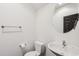 Well-lit half bath with a white toilet and a round mirror above the contemporary sink at 7601 E Roosevelt St # 1007, Scottsdale, AZ 85257
