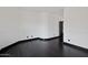 A simple room with hardwood floors, white walls, and a single black door at 7601 E Roosevelt St # 1007, Scottsdale, AZ 85257