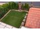 Beautiful artificial grass backyard bordered by lush greenery and stone paver accents at 936 E Gila Ln, Chandler, AZ 85225