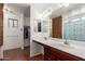 Bathroom featuring double sinks, a large mirror, shower/tub, and walk-in closet at 11410 W Davis Ln, Avondale, AZ 85323
