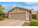 Attached two-car garage with a neutral door and desert landscaping at 11410 W Davis Ln, Avondale, AZ 85323
