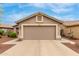 Attached two-car garage with a neutral door and desert landscaping at 11410 W Davis Ln, Avondale, AZ 85323