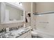 Well-lit bathroom with white fixtures, granite countertop, framed mirror, and combination tub and shower at 11650 W Pincushion Ct, Surprise, AZ 85378