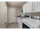 Functional laundry room features a washer and dryer, white cabinets, granite countertop and light wood floors at 11650 W Pincushion Ct, Surprise, AZ 85378