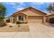 A tan one-story home featuring a well-kept yard and a two-car garage under a blue sky at 11808 E Clinton St, Scottsdale, AZ 85259