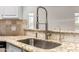 Close-up on the kitchen sink with granite countertops and travertine backsplash at 11808 E Clinton St, Scottsdale, AZ 85259