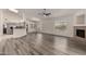 Open concept living room featuring wood floors, a ceiling fan, and a corner fireplace at 11808 E Clinton St, Scottsdale, AZ 85259