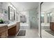 Bathroom with dual sinks, marble-tiled walls, a soaking tub, and a glass-enclosed shower at 1333 E Bermuda Bay Ct, Gilbert, AZ 85234