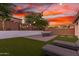 Picturesque backyard boasts vibrant artificial grass, ambient string lighting, and a stylish patio with dining set at 13720 W Amberwing St, Peoria, AZ 85383