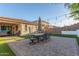 Backyard with an outdoor dining set on a paver patio, artificial grass, and string lights for a cozy ambiance at 13720 W Amberwing St, Peoria, AZ 85383