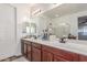 Bright bathroom featuring dual sinks, dark wood cabinets, and a large mirror with vanity lighting above at 13720 W Amberwing St, Peoria, AZ 85383