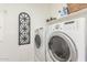 Bright laundry room with modern washer and dryer and functional shelving at 13720 W Amberwing St, Peoria, AZ 85383