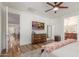 Bright main bedroom featuring wood floors, ceiling fan, television and adjacent bathroom at 13720 W Amberwing St, Peoria, AZ 85383