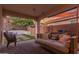 Cozy covered patio showcases an outdoor daybed swing and a serene view of the beautifully landscaped backyard at 13720 W Amberwing St, Peoria, AZ 85383