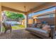 Serene covered patio showcases a relaxing outdoor daybed swing and views of a beautifully landscaped backyard at 13720 W Amberwing St, Peoria, AZ 85383