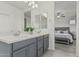 Bathroom with double vanity, gray cabinets, and a view into the main bedroom at 14870 W Encanto Blvd # 1061, Goodyear, AZ 85395