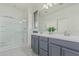 Bright bathroom featuring a glass-enclosed shower and double vanity with gray cabinets at 14870 W Encanto Blvd # 1061, Goodyear, AZ 85395