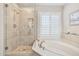 Bright bathroom featuring a tiled shower, soaking tub, and plantation shutters at 15815 N 4Th Dr, Phoenix, AZ 85023