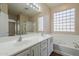 Bright bathroom featuring dual vanities, a large mirror, soaking tub, and glass block windows at 15902 W Hearn Rd, Surprise, AZ 85379