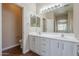 Bright bathroom featuring dual sinks, white cabinets, and a large mirror at 15902 W Hearn Rd, Surprise, AZ 85379