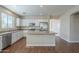 Open kitchen with white cabinets, stainless appliances, island, and wood-look floors at 15902 W Hearn Rd, Surprise, AZ 85379