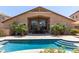 A backyard features a pool with fountains, outdoor seating, and lush landscaping creating a serene oasis at 16280 W Durango St, Goodyear, AZ 85338