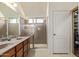 Bathroom featuring double sinks, a glass-enclosed shower, and tiled floors, complemented by neutral wall tones at 16280 W Durango St, Goodyear, AZ 85338