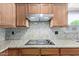 Close-up of a kitchen featuring granite counters, a smooth cooktop, and wooden cabinets at 16280 W Durango St, Goodyear, AZ 85338