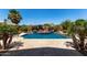 Serene backyard pool surrounded by lush landscaping, a rock feature, and ample patio space for entertaining at 16280 W Durango St, Goodyear, AZ 85338