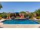 Backyard swimming pool featuring a water feature, stone surround, lush landscaping, and an umbrella for shade at 16280 W Durango St, Goodyear, AZ 85338