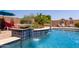 Luxury pool featuring a tiled water feature, lush landscaping, and comfortable seating creating a resort-like backyard at 16280 W Durango St, Goodyear, AZ 85338