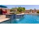 Luxury pool featuring a tiled water feature, lush landscaping, and comfortable seating creating a resort-like backyard at 16280 W Durango St, Goodyear, AZ 85338