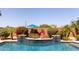 Backyard pool featuring a water feature, stone surround, lush landscaping, and an umbrella for shade at 16280 W Durango St, Goodyear, AZ 85338